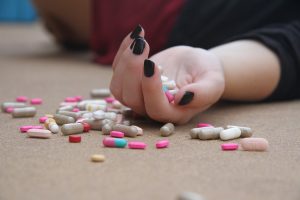 Upturned hand on the floor with various spilt pills spread out