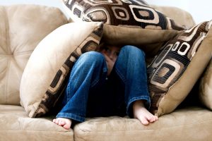 Child hiding under cushions on a sofa